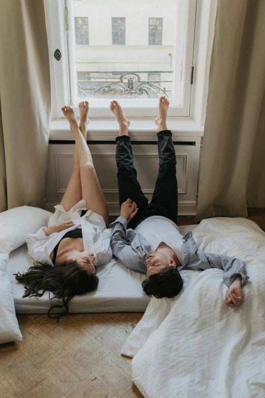 two women laying on a mattress with their legs crossed