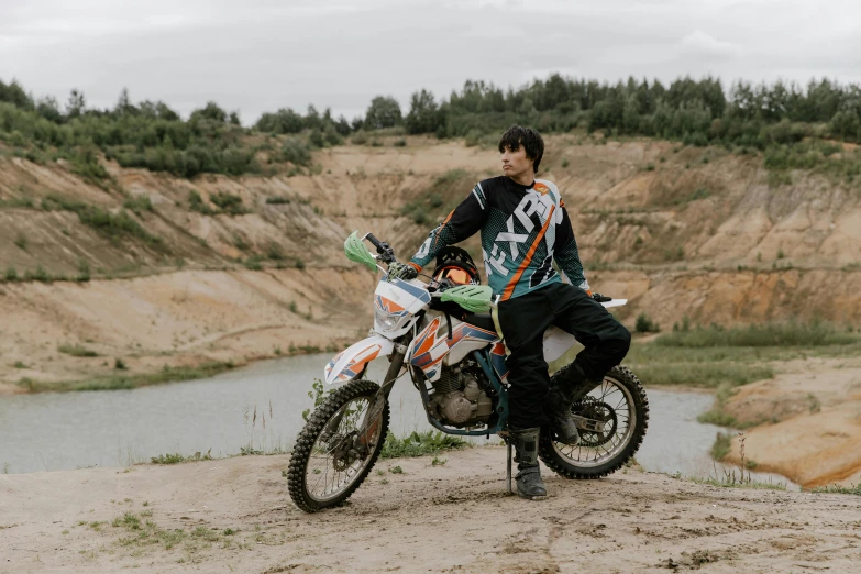 a boy sitting on a motorbike by the side of a mountain