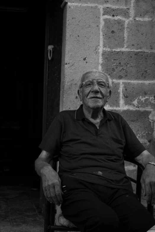 an old man sits on his chair outside