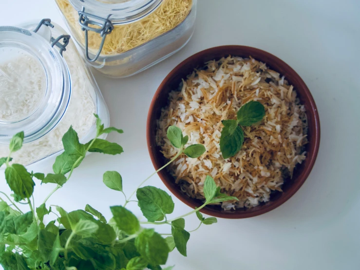 green leaves and rice are in bowls with lids