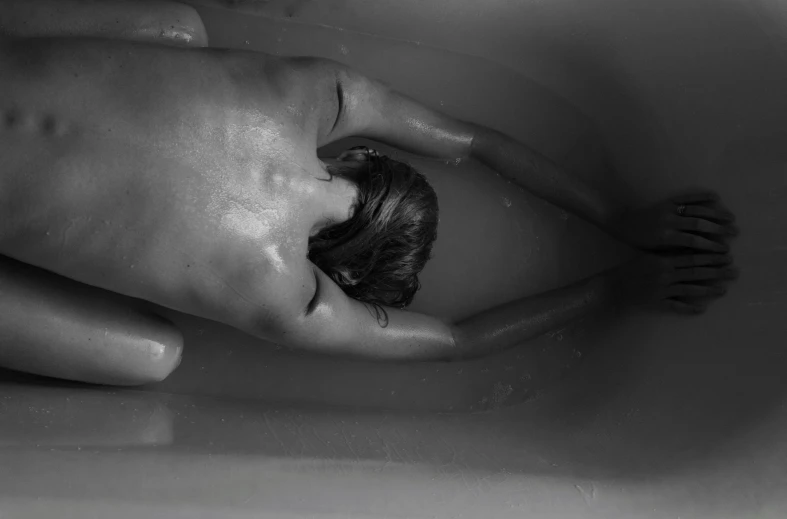 black and white pograph of a person sitting in a bath tub