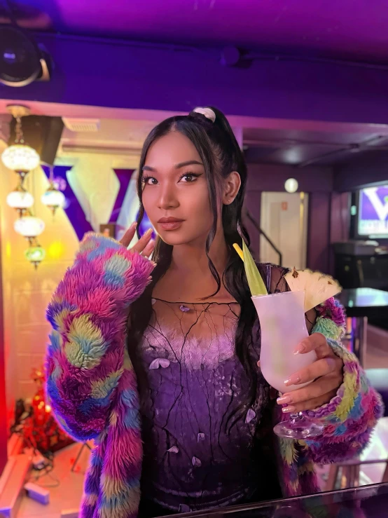 a woman in a purple dress holding up an orange juice in her right hand