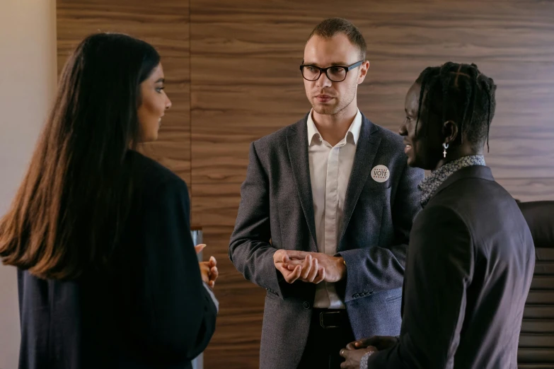 three people stand in a room, talking