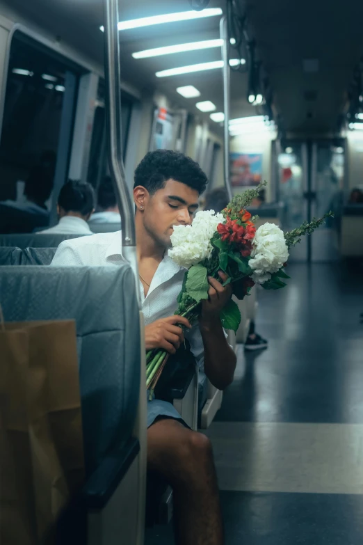 a man sitting on a bus while holding flowers