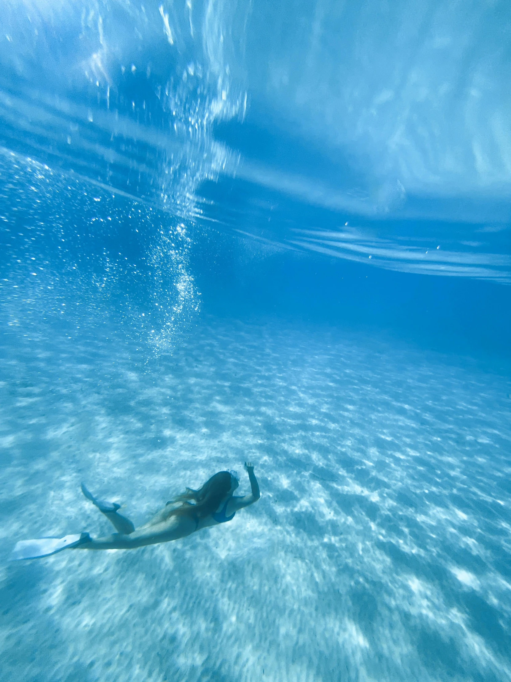 a girl swims in the ocean under water