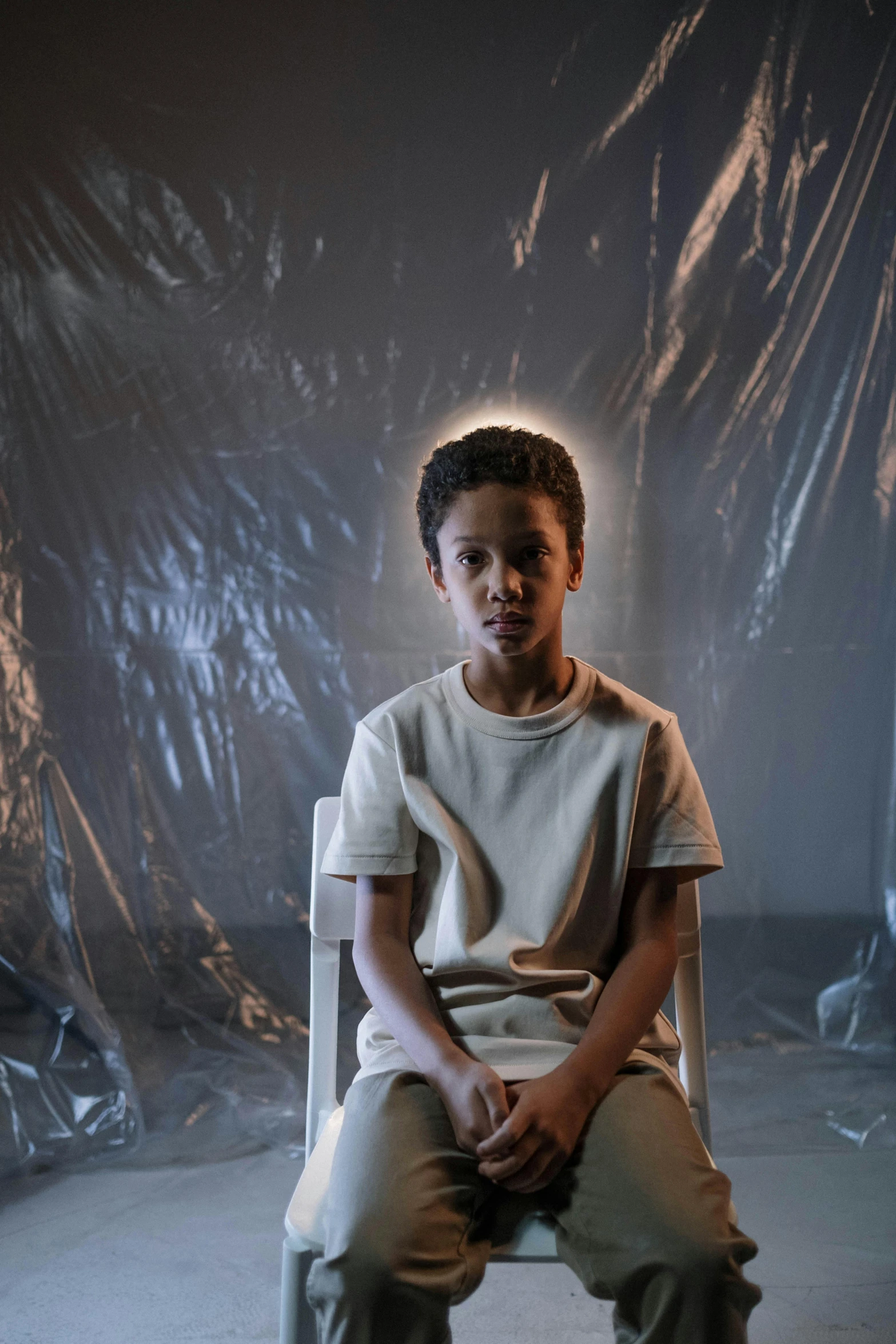 a child sitting on a chair in front of a dark backdrop