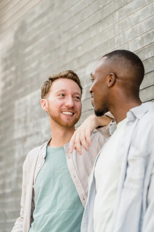 two males posing for a portrait in front of a brick wall