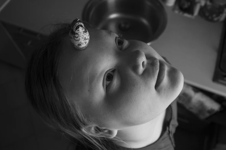 a child stares up to the camera while putting his head in an old cap