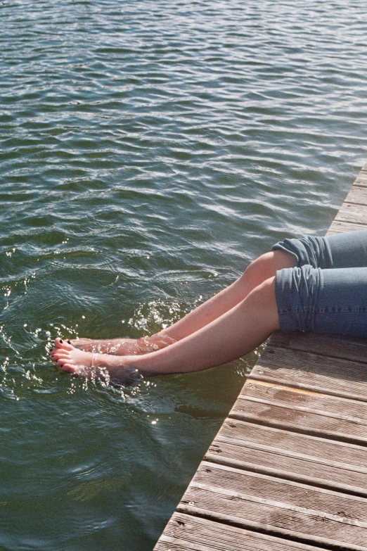 woman in shorts sitting on a dock near the water