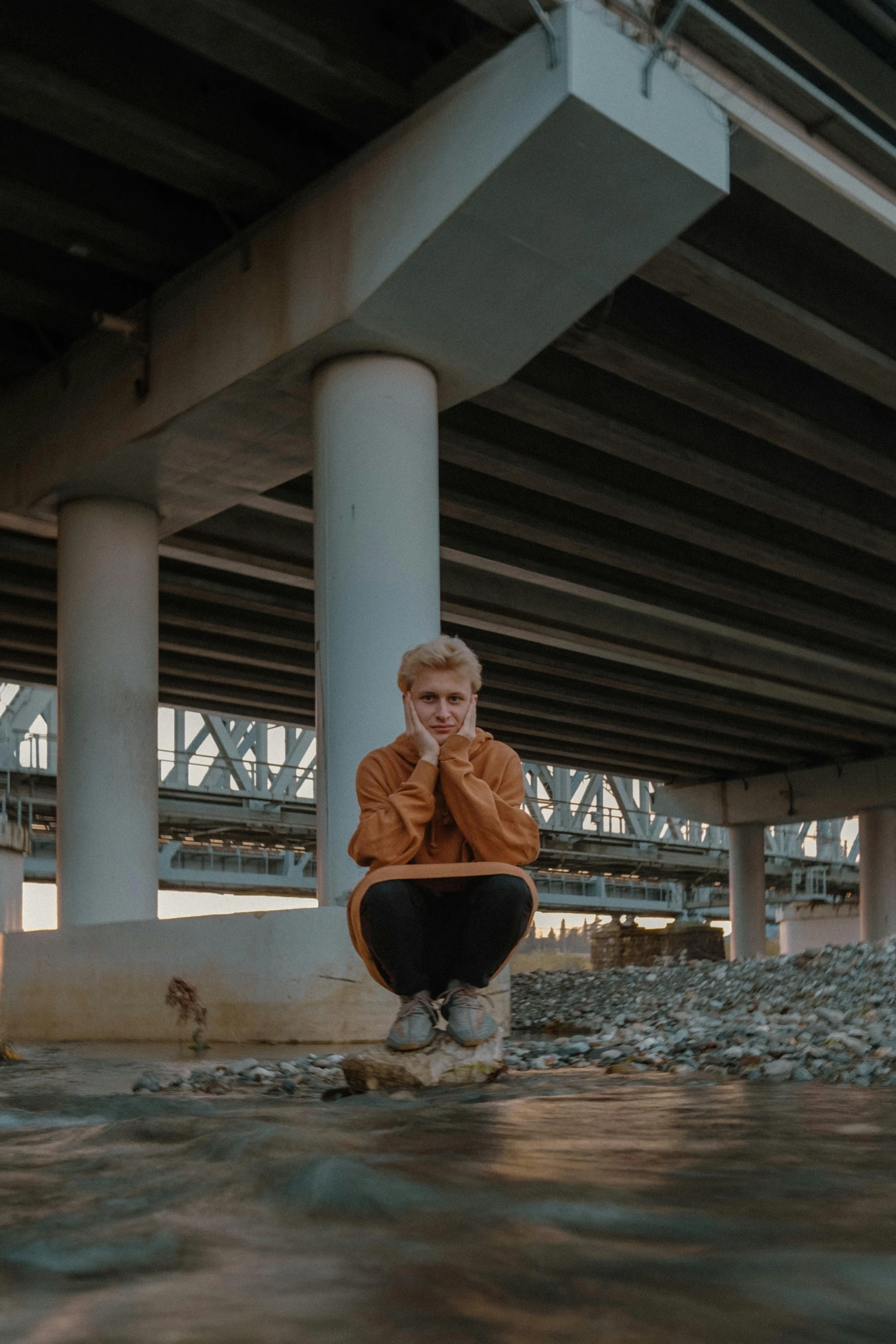 a young person kneeling down under an overpass