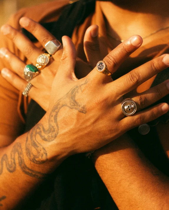 the woman wears a stack of rings as she holds her arm