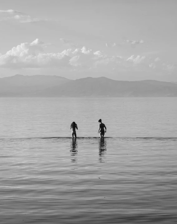 two people are wading through the water near a island