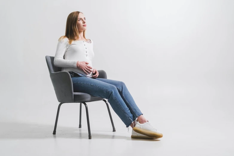 the pregnant woman sits in an armchair, looking up