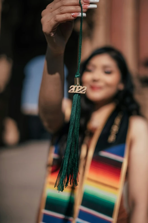 a woman wearing a green tassel holds up her cigarette