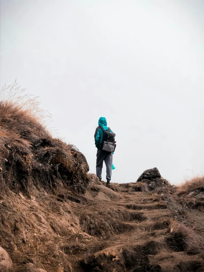 a man walking up the hill wearing a jacket and carrying a backpack