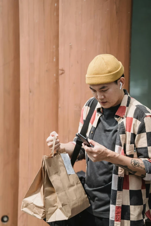 a young person holding a bag looking at a cell phone