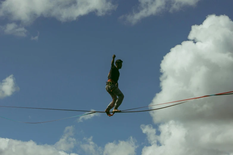 a person is on a high wire with hands raised above him