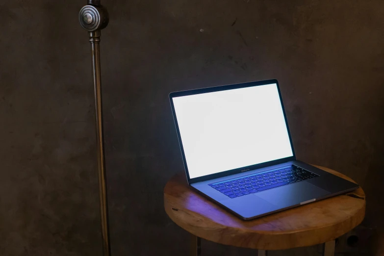 a laptop computer sits on a round table with a lamp nearby