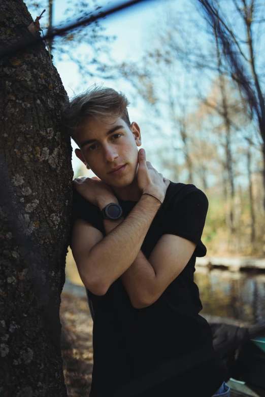 a man leaning against a tree in the woods