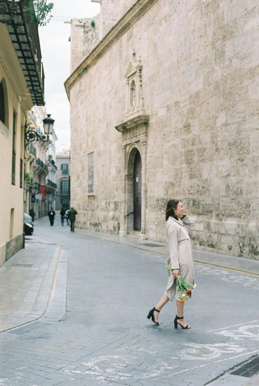 woman walking down a sidewalk next to a building