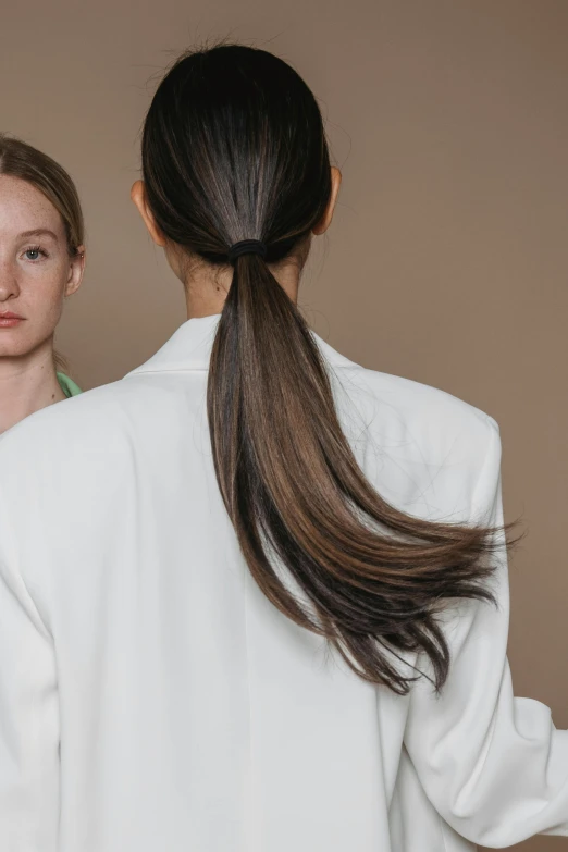 a woman with long brown hair is standing next to another person