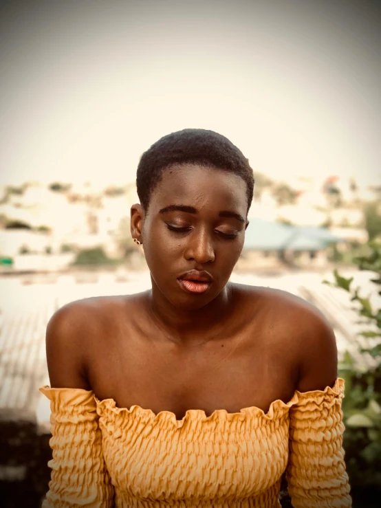 a woman in an orange off shoulder top staring down at her phone