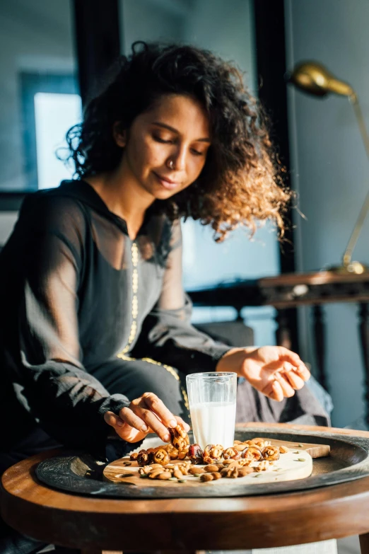 a person sits at a table while filling her plate with cereal and milk