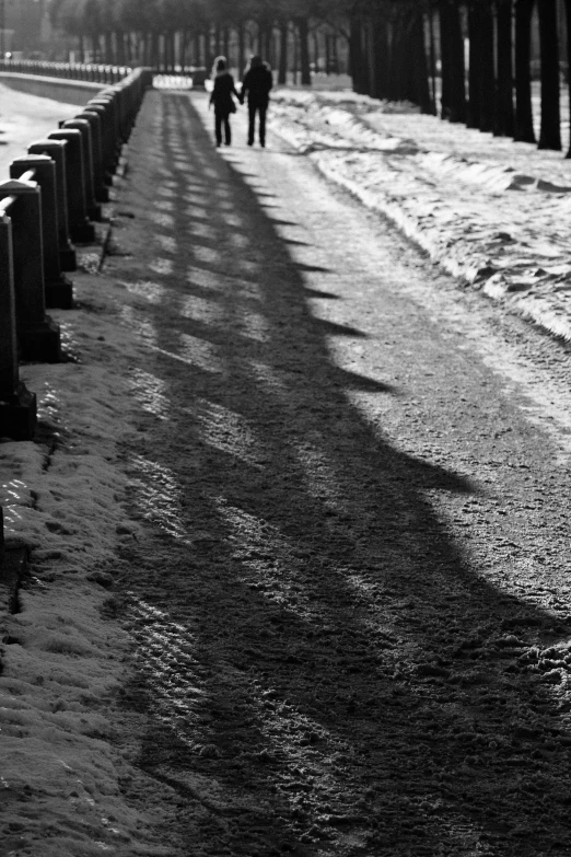 two people are walking on the snow covered sidewalk