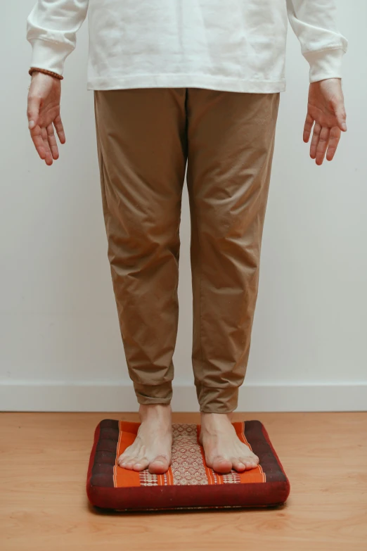 a man stands on a scale while wearing tan pants
