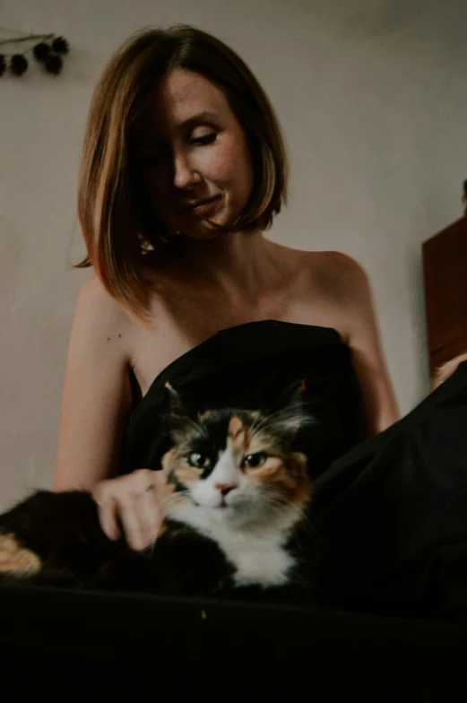 a woman with a cat sitting on her bed