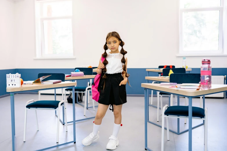 a girl in an empty classroom with tables and chairs