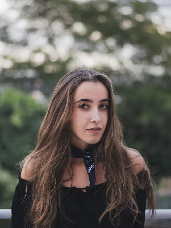 a beautiful young woman posing for a po in front of trees