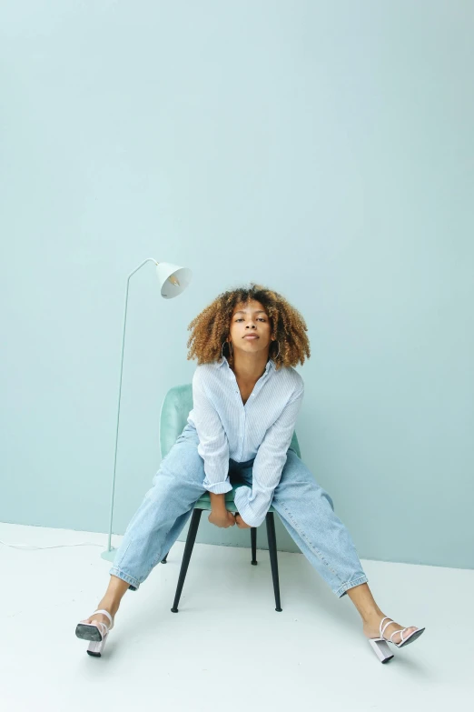 woman sitting on chair with one leg up and wearing a white shirt