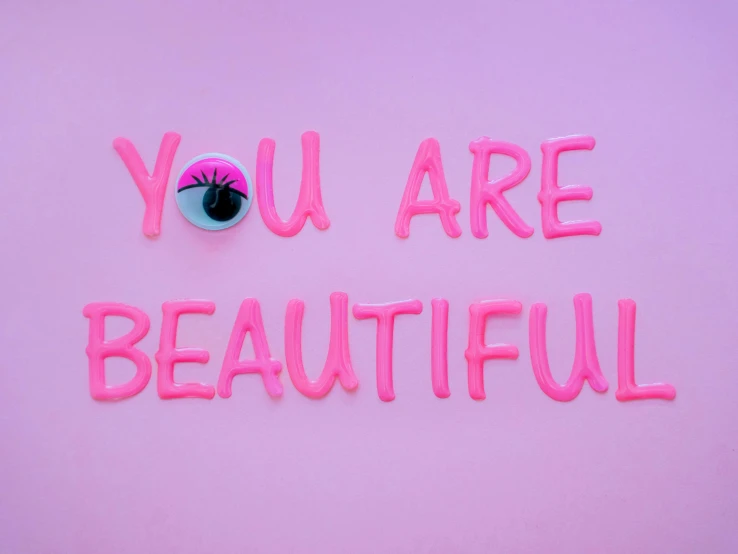 the word you are beautiful written in neon pink type