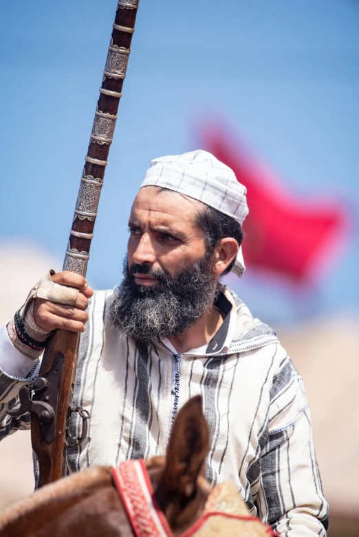 an old man holding a rifle and a horse