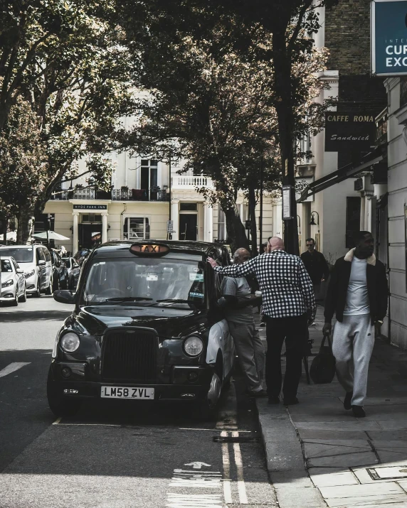 several people walk down a sidewalk past a car and signs