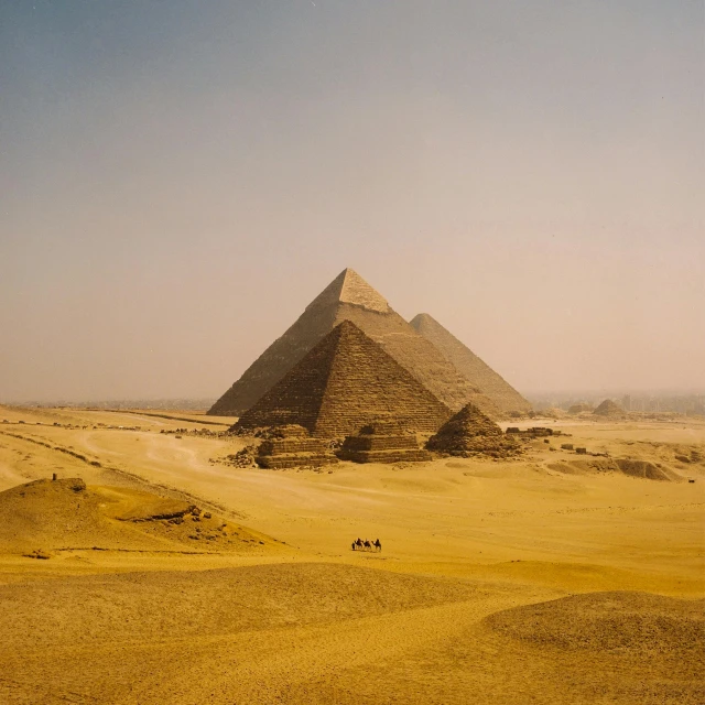 several pyramids sitting in the desert under a blue sky