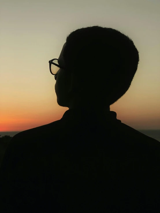 silhouette of a man with glasses and tie at sunset