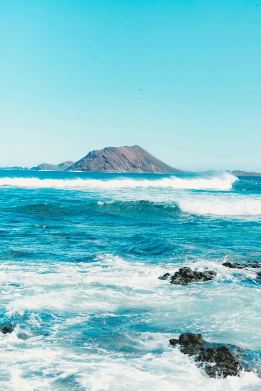 ocean with rocks in front and one mountain out on the other