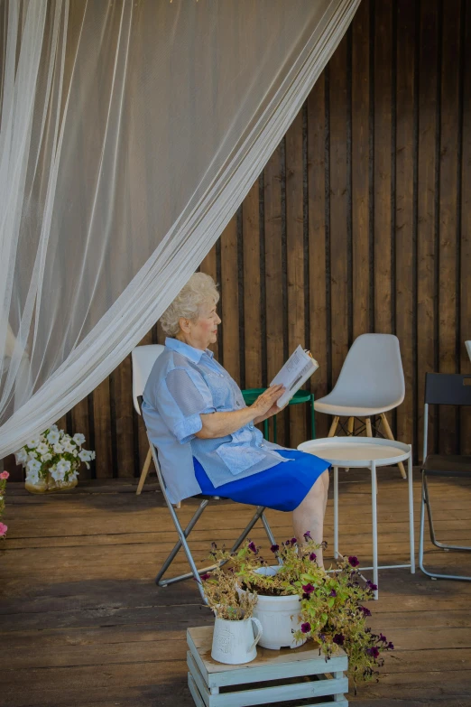 an elderly lady sitting in a chair reading her book