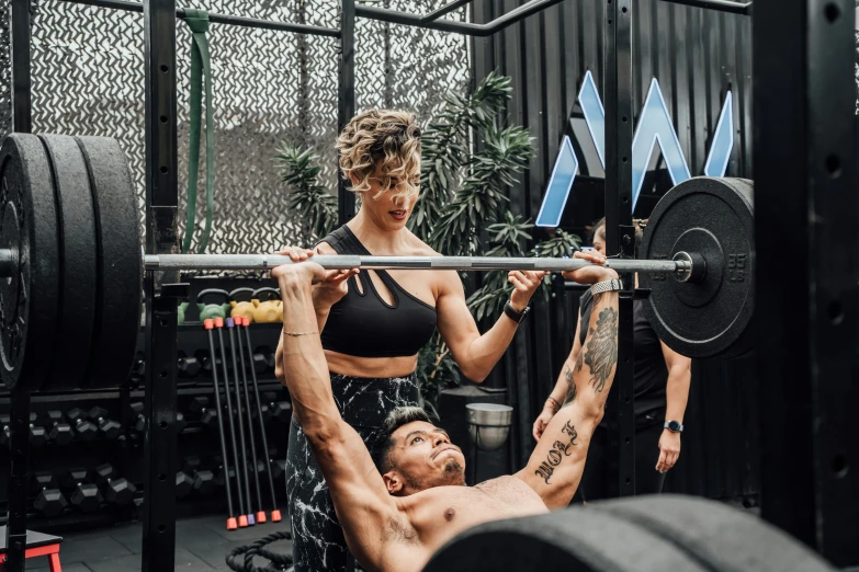 a man holding a barbell next to a woman in the gym