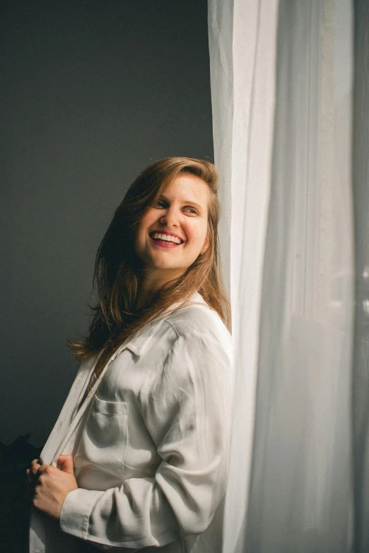 a woman standing in front of a curtain, smiling