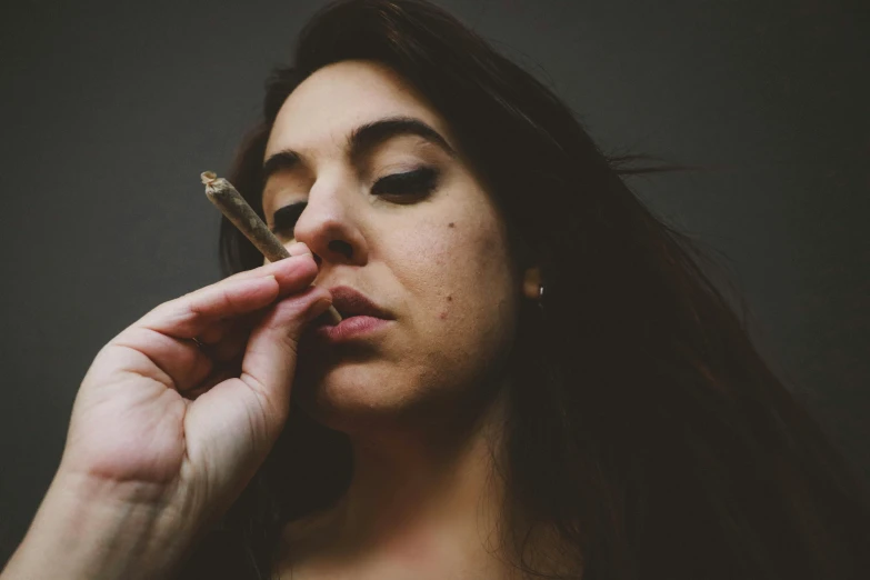 a woman with long hair holding a cigarette