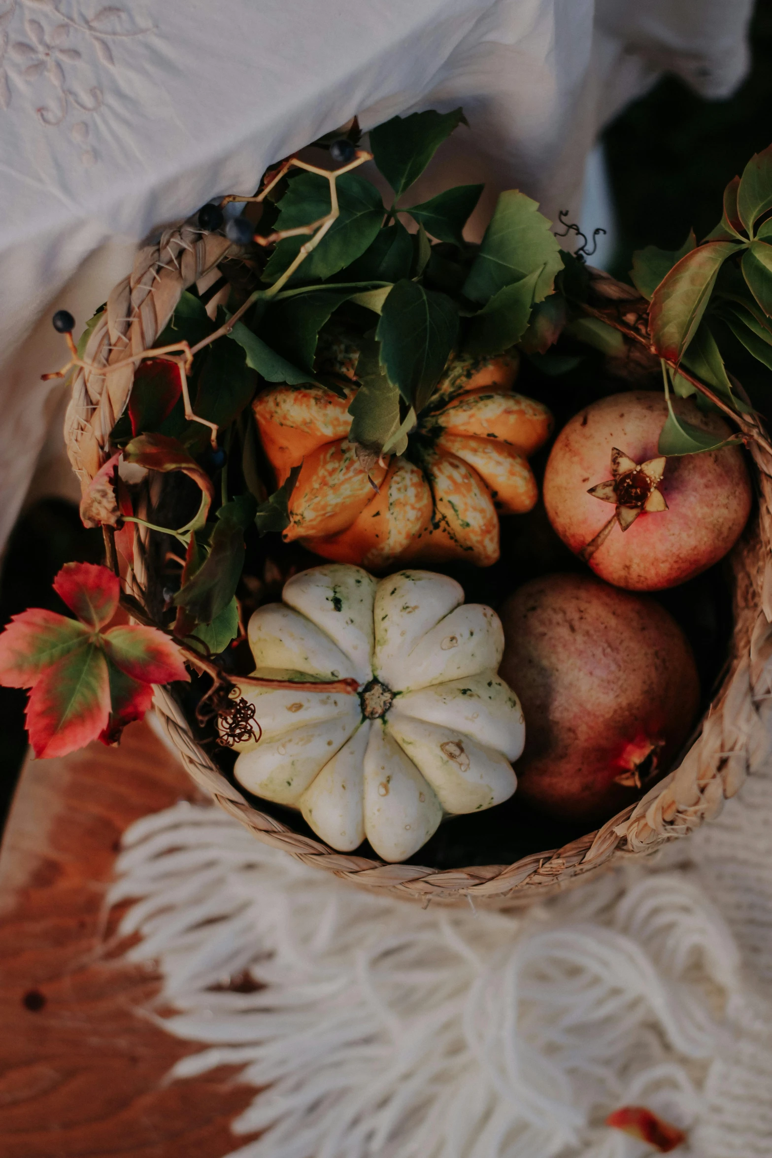 a woven bowl filled with miniature pumpkins and pomegranates