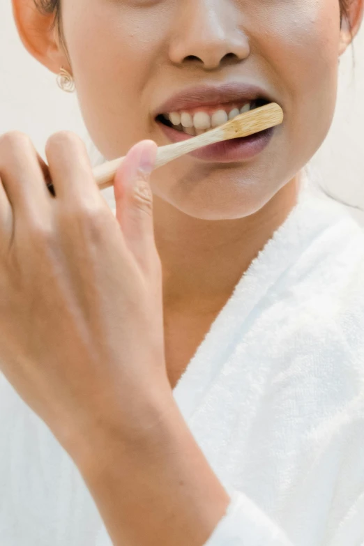 an asian girl in white robes holding a tooth brush