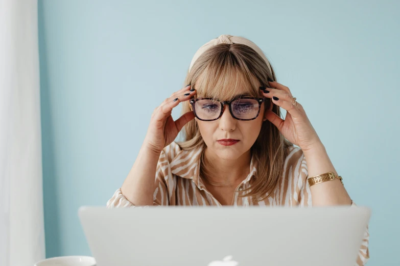 the woman is wearing glasses and looking at her laptop