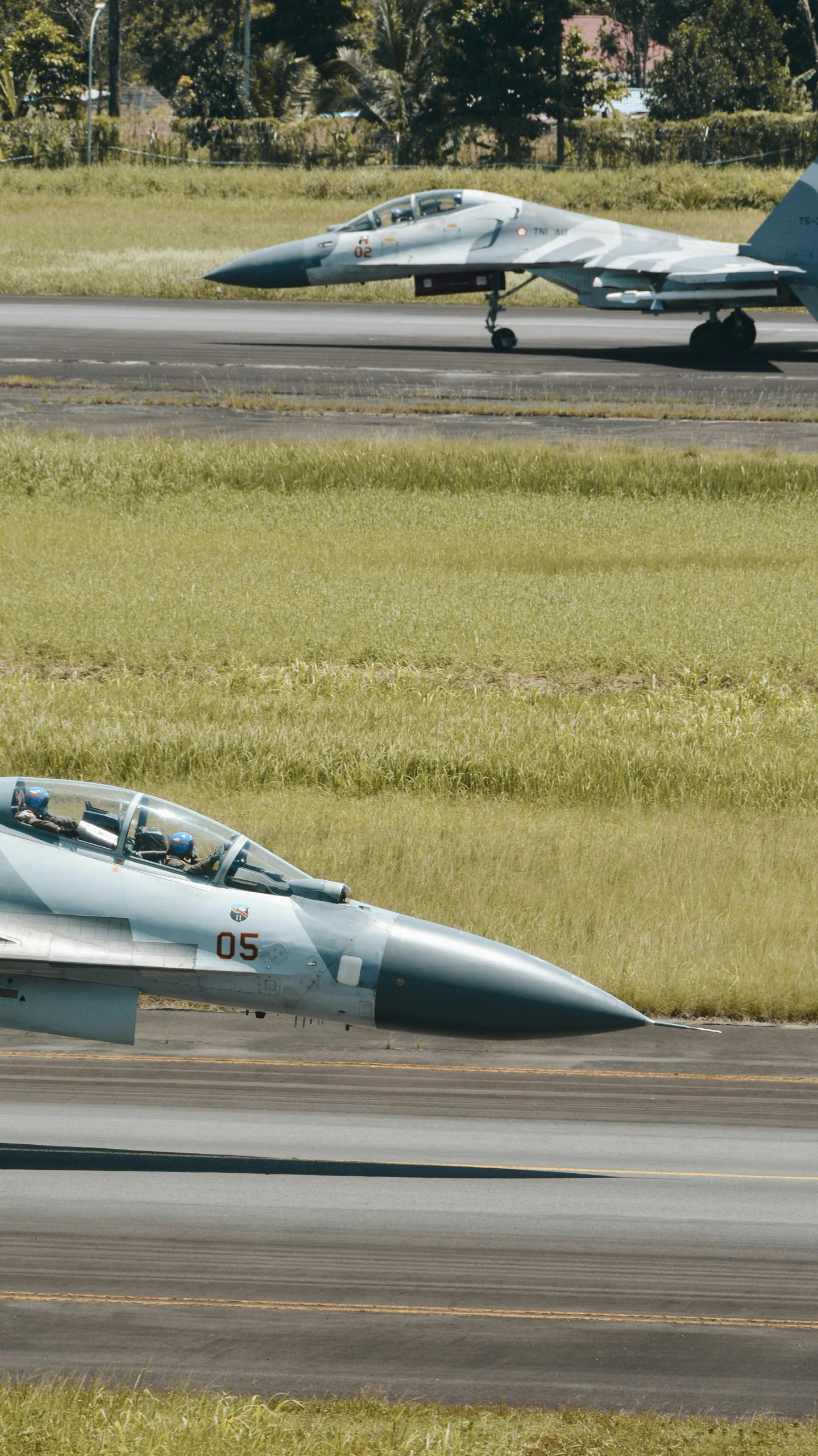 two fighter jets are in a field with grassy fields