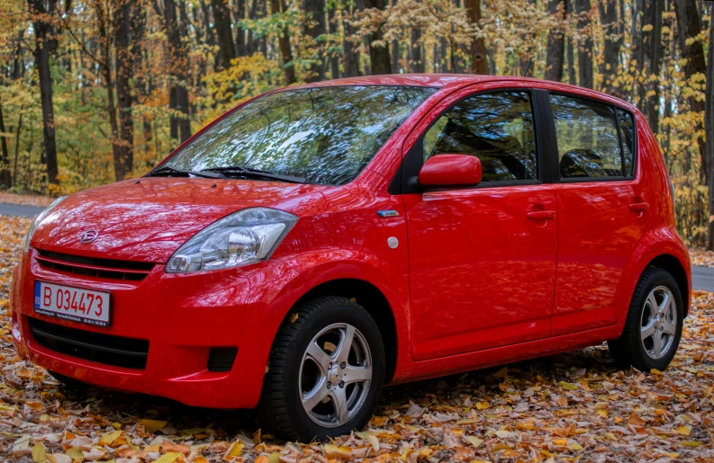 a red car parked on the side of the road in front of trees