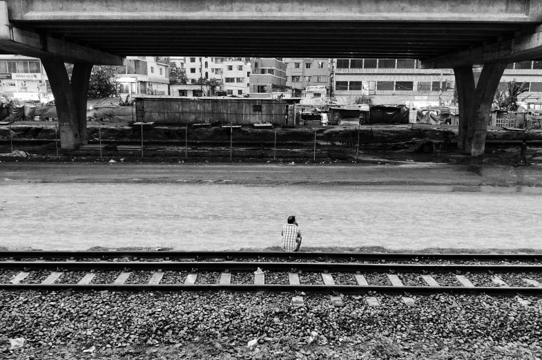 a person standing on a railway track under an overpass