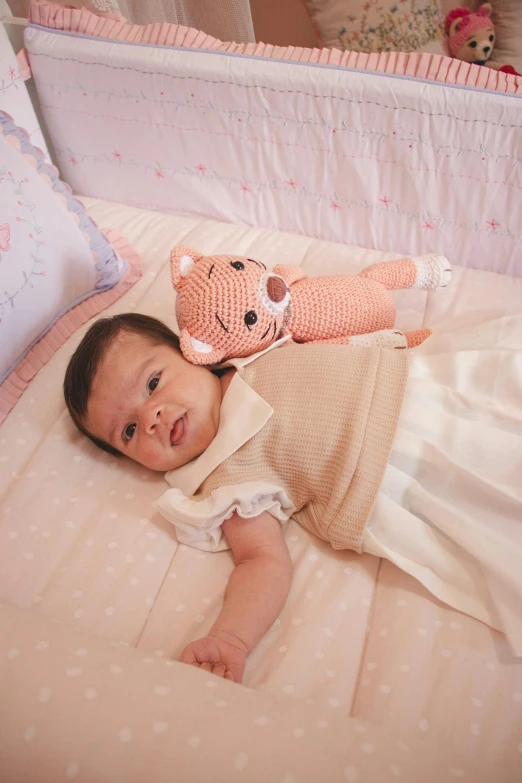 a little baby in bed with a knit cat